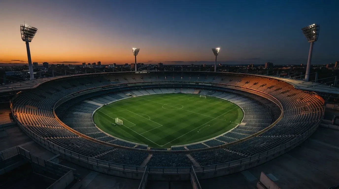 An empty football stadium with floodlight masts at dusk