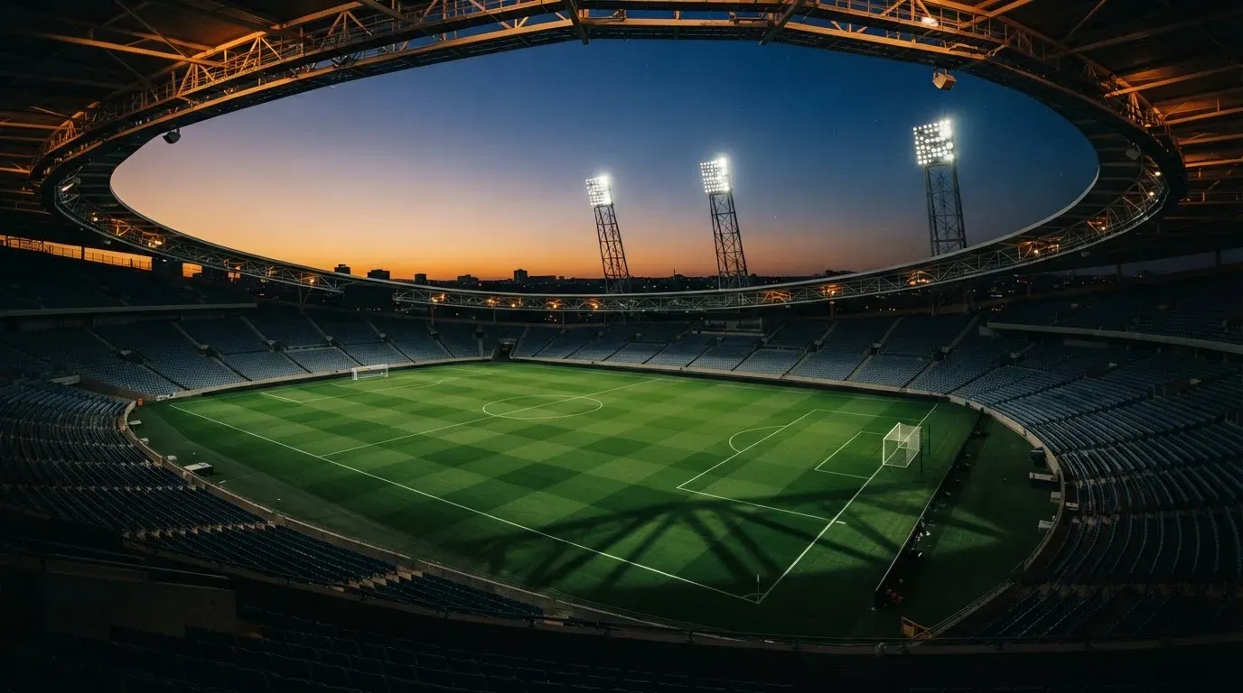 An empty football stadium with floodlight masts at dusk