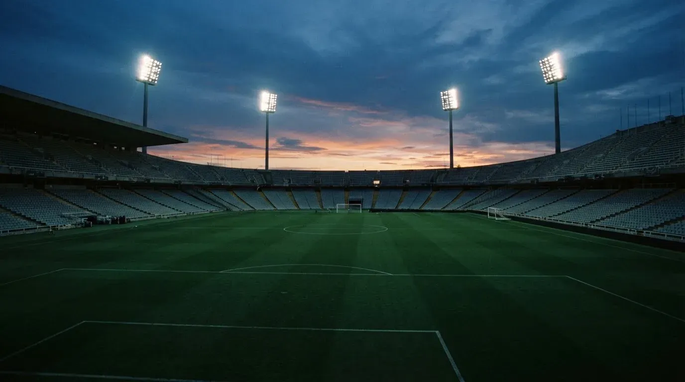 An empty football stadium with floodlight masts at dusk