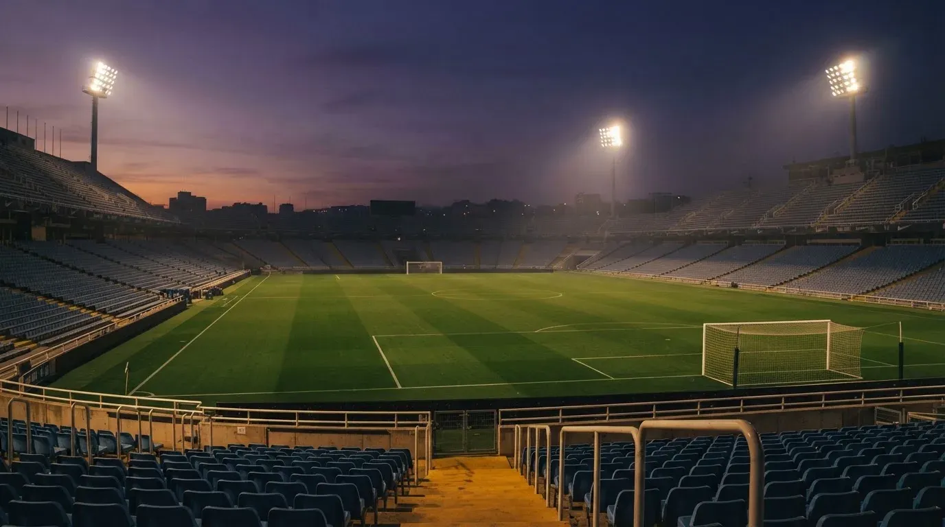 An empty football stadium with floodlight masts at dusk