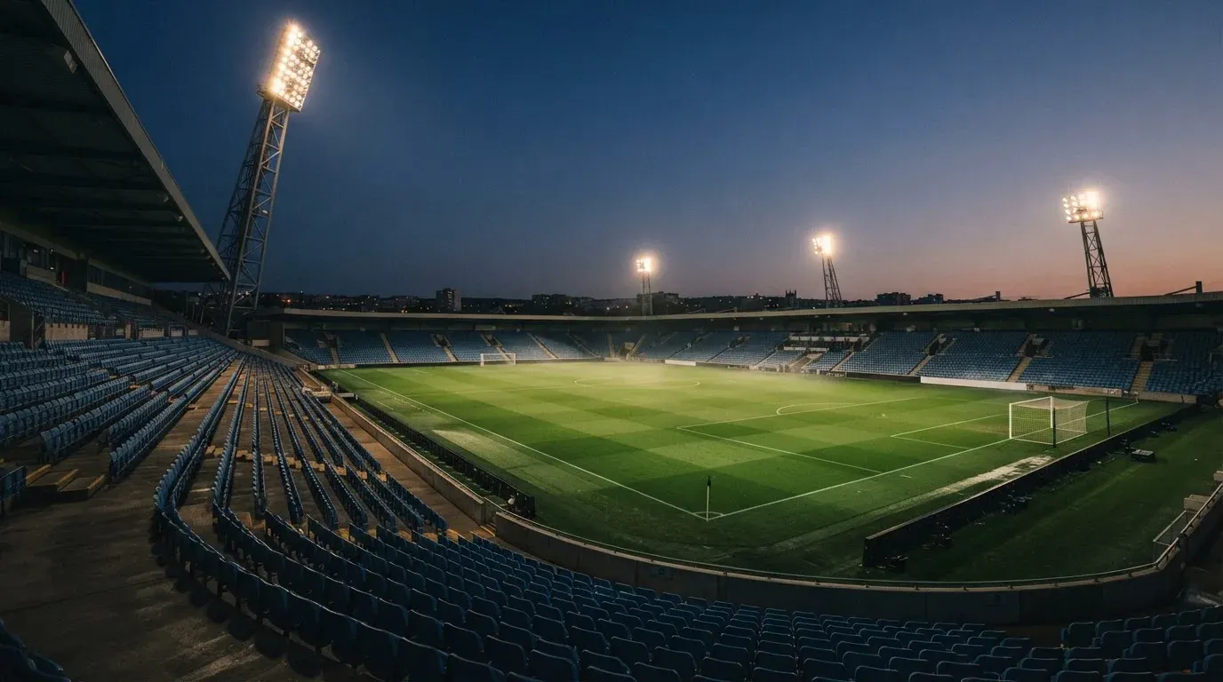 An empty football stadium with floodlight masts at dusk