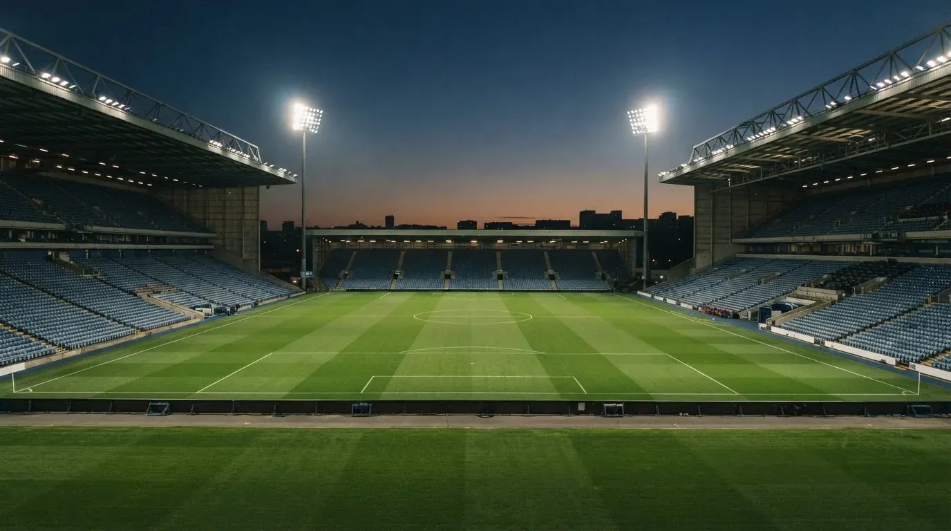 An empty football stadium with floodlight masts at dusk