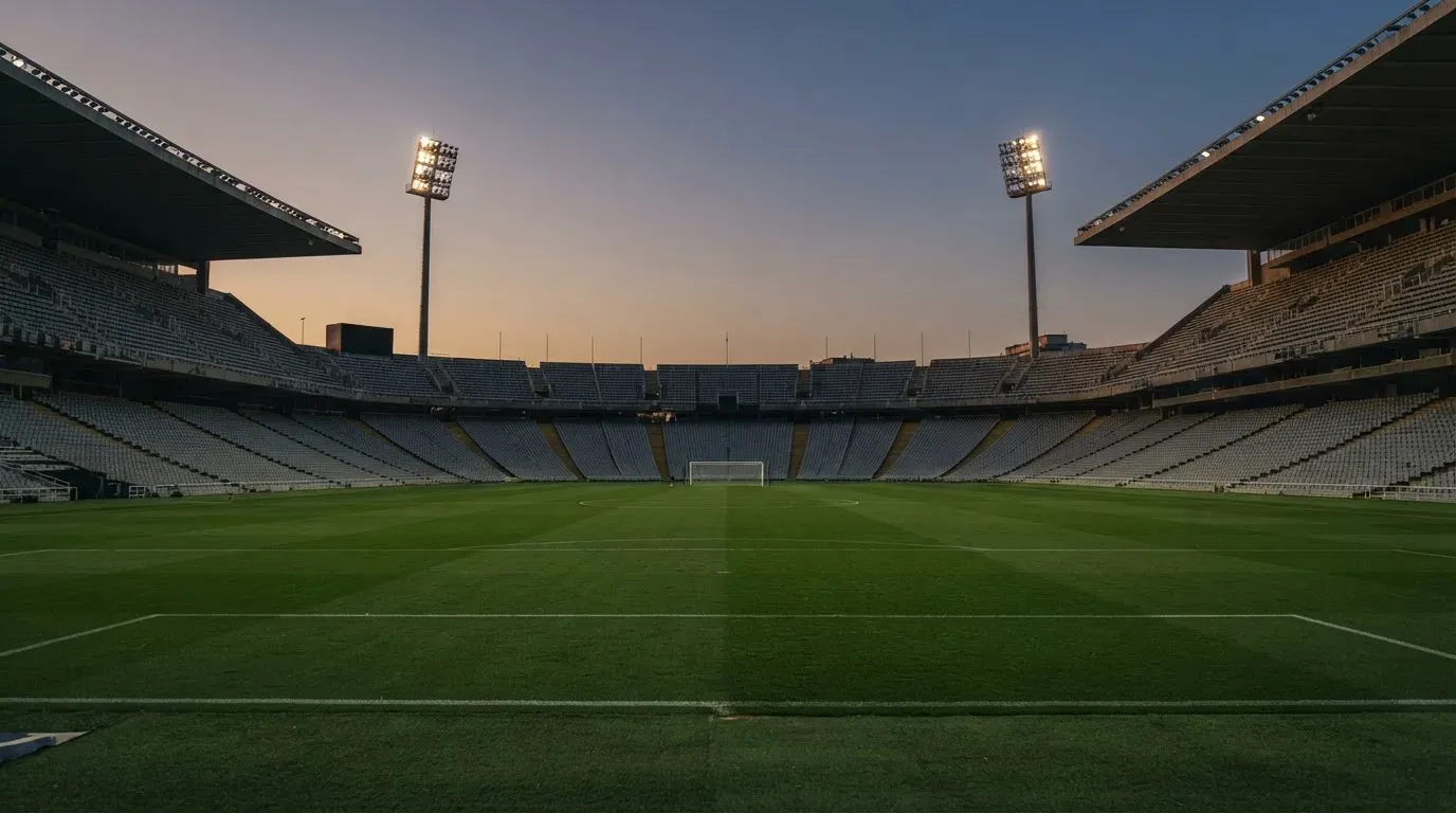An empty football stadium with floodlight masts at dusk