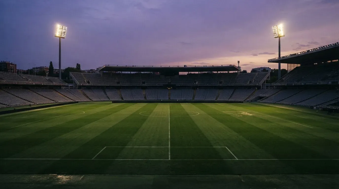 An empty football stadium with floodlight masts at dusk