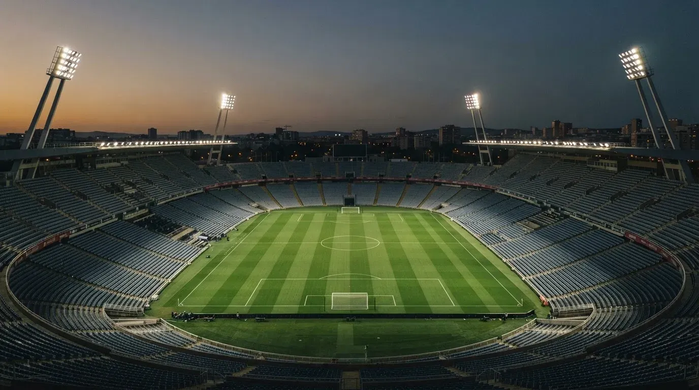 An empty football stadium with floodlight masts at dusk