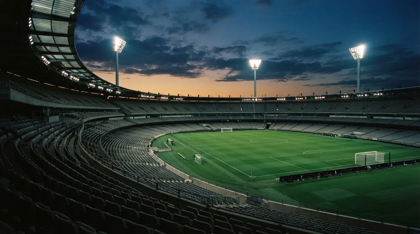 An empty football stadium with floodlight masts at dusk