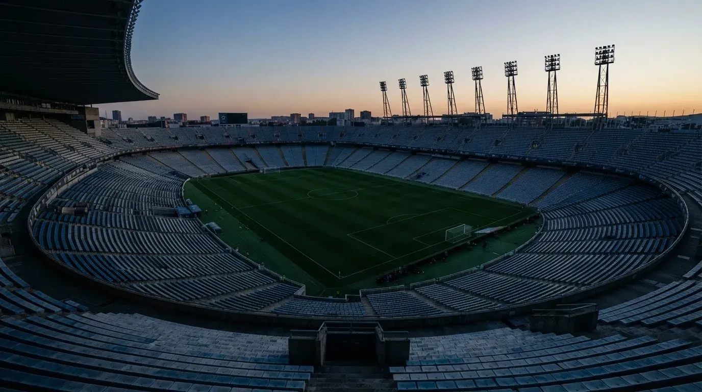 An empty football stadium with floodlight masts at dusk