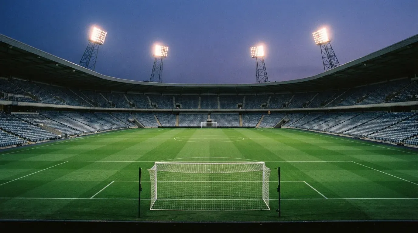 An empty football stadium with floodlight masts at dusk