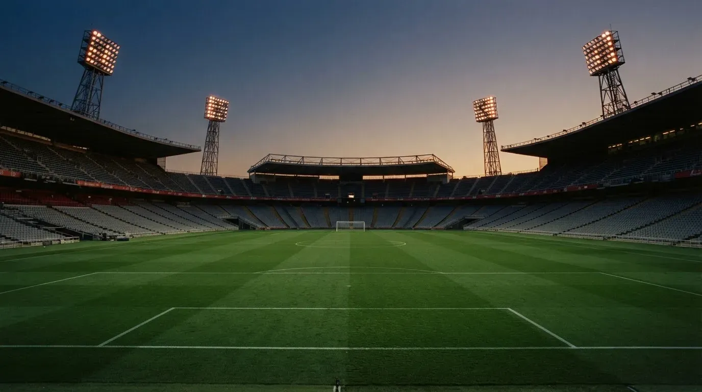 An empty football stadium with floodlight masts at dusk