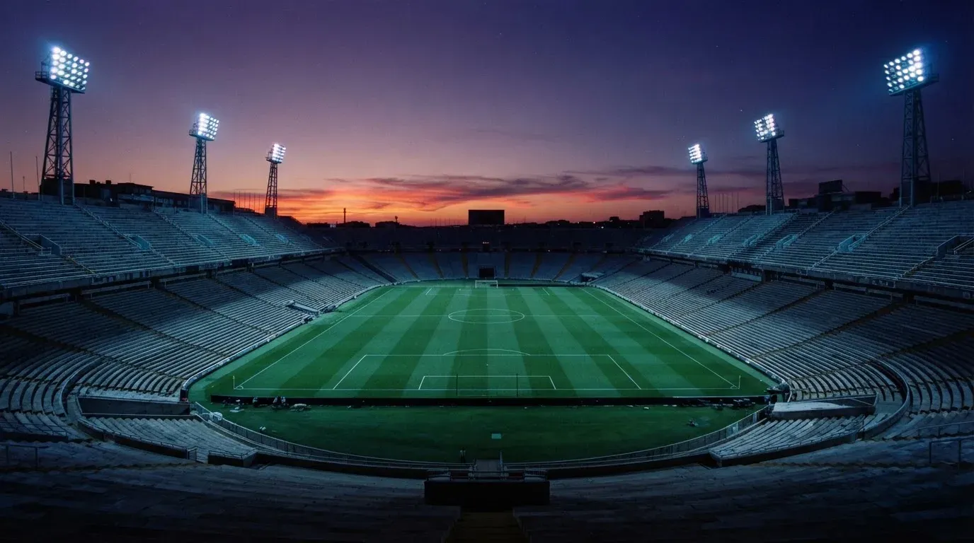 An empty football stadium with floodlight masts at dusk