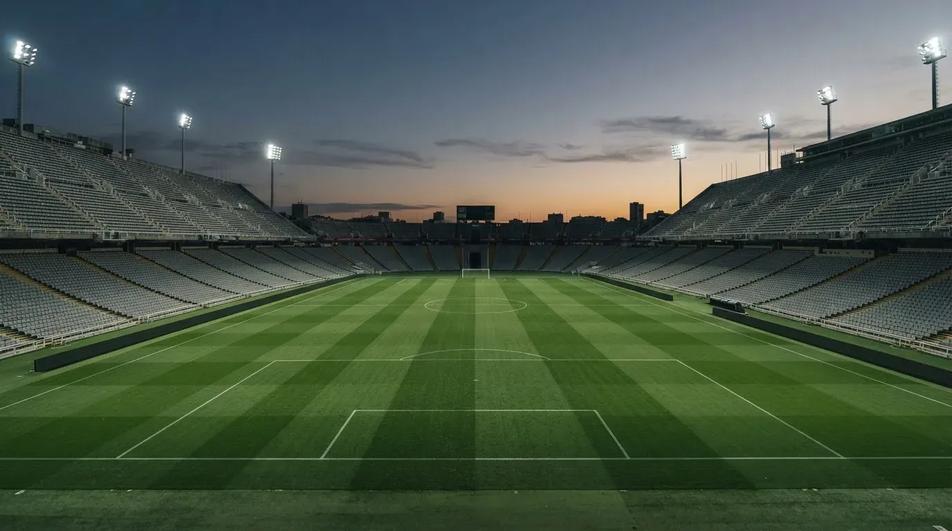 An empty football stadium with floodlight masts at dusk
