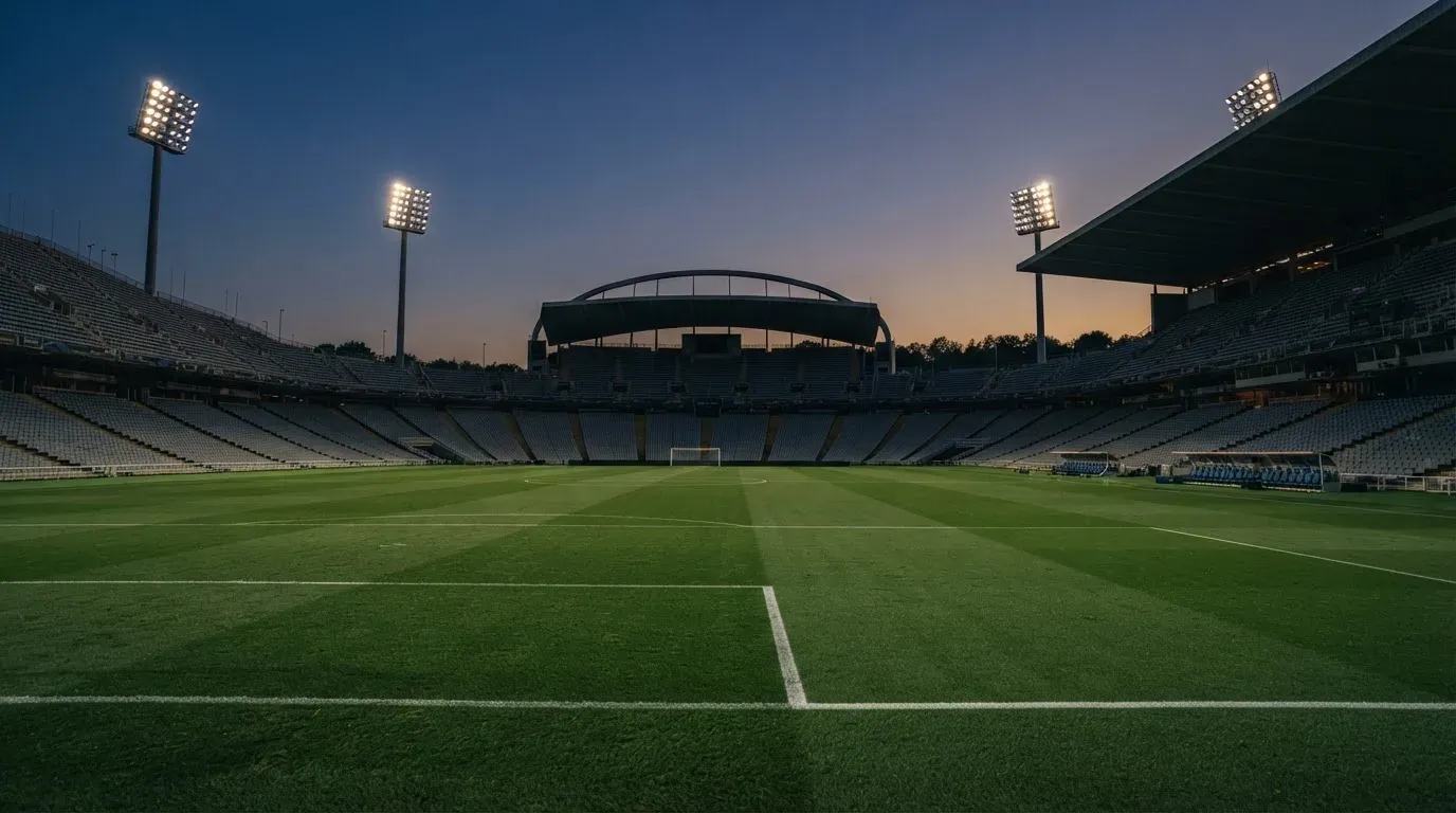 An empty football stadium with floodlight masts at dusk