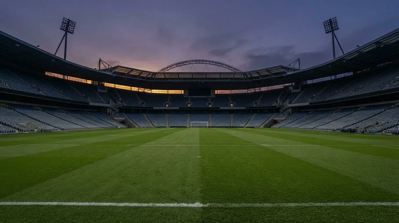 An empty football stadium with floodlight masts at dusk