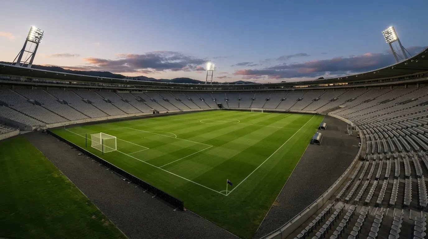 An empty football stadium with floodlight masts at dusk