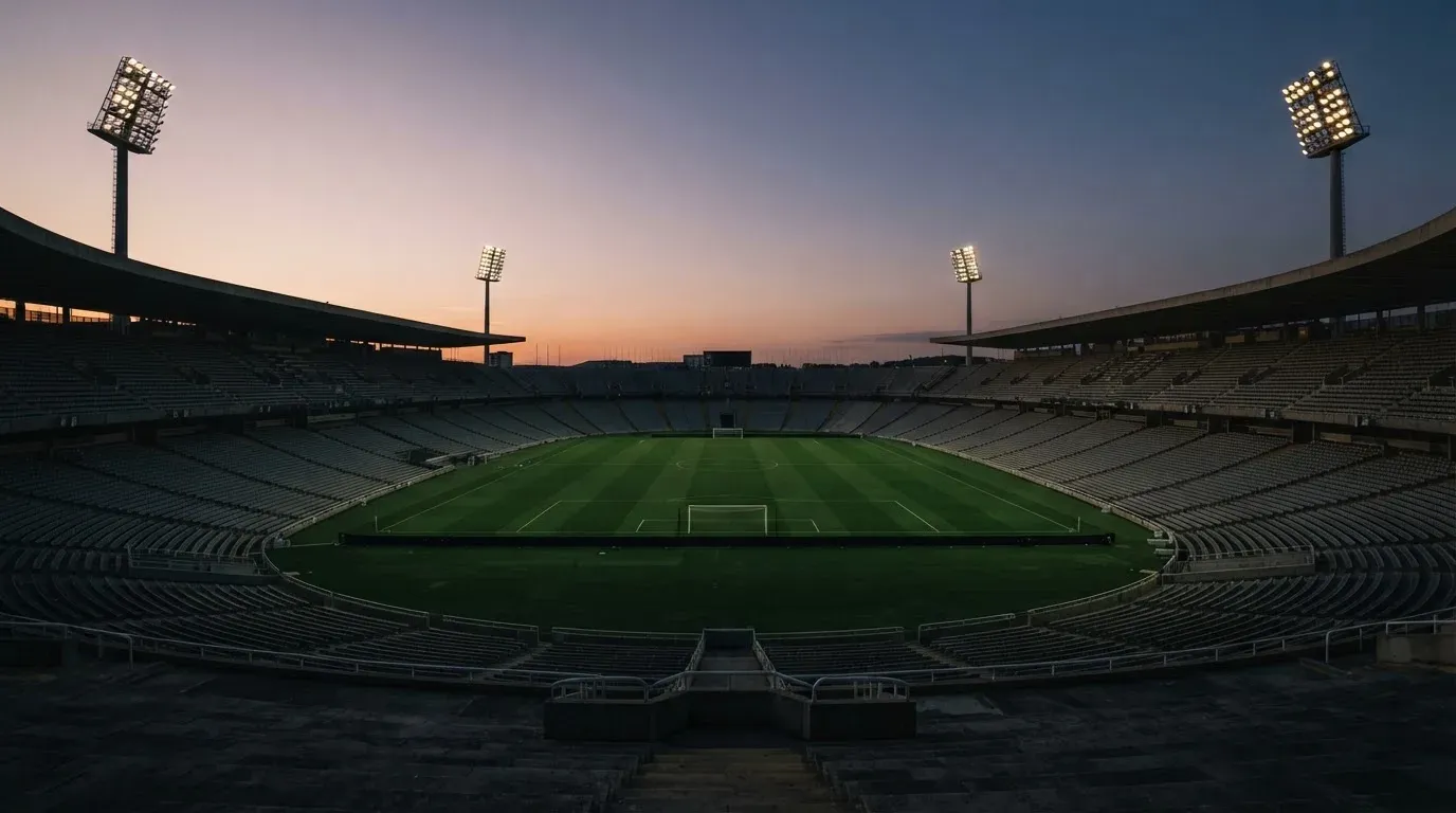 An empty football stadium with floodlight masts at dusk