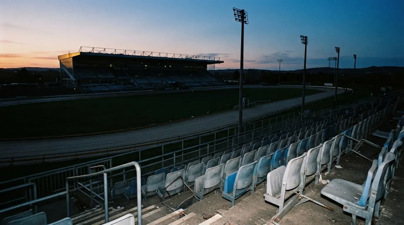An empty football stadium with floodlight masts at dusk