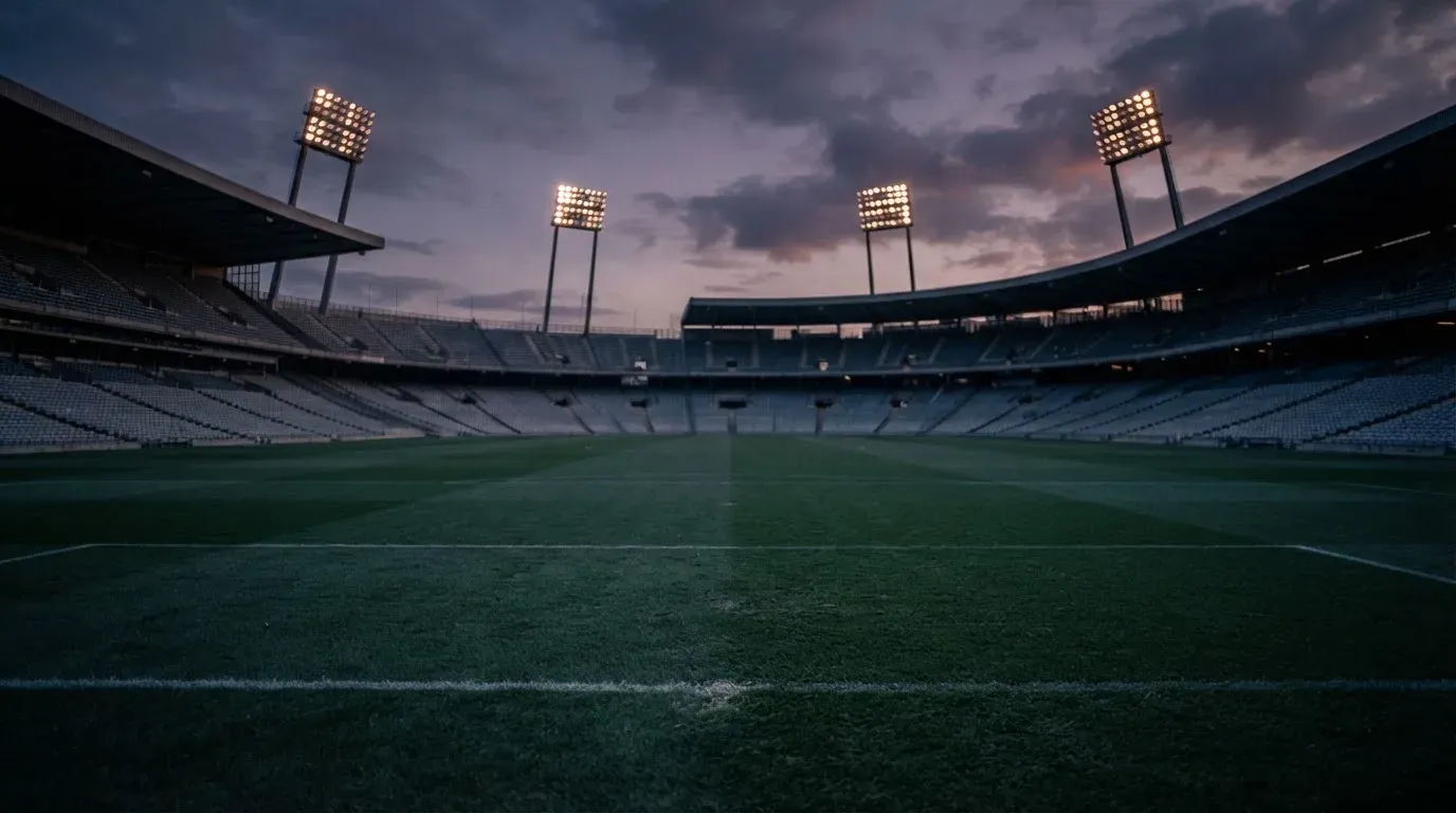 An empty football stadium with floodlight masts at dusk
