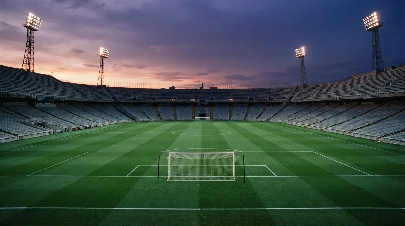 An empty football stadium with floodlight masts at dusk