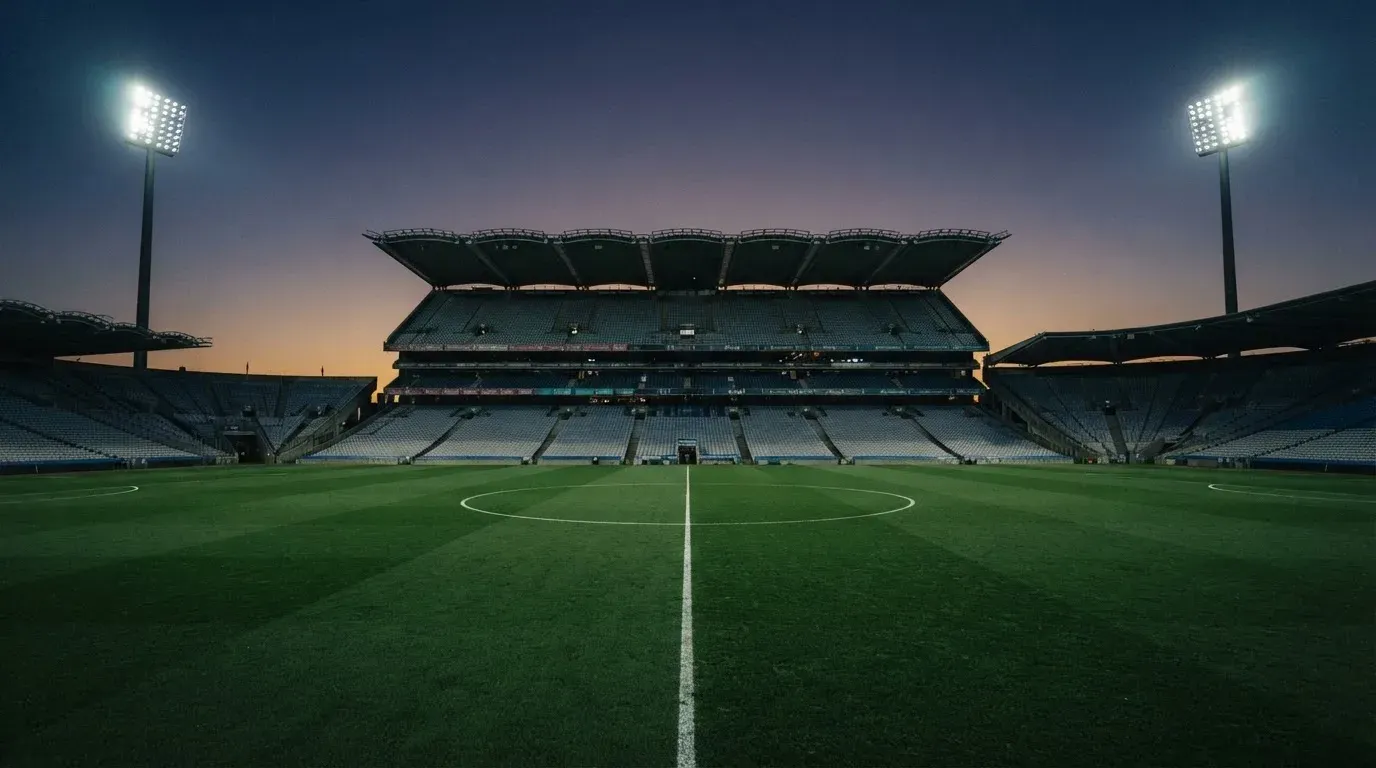 An empty football stadium with floodlight masts at dusk