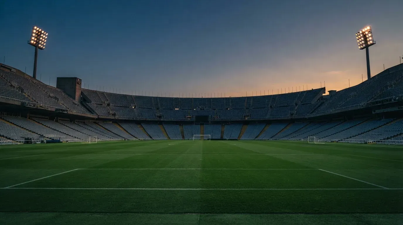 An empty football stadium with floodlight masts at dusk