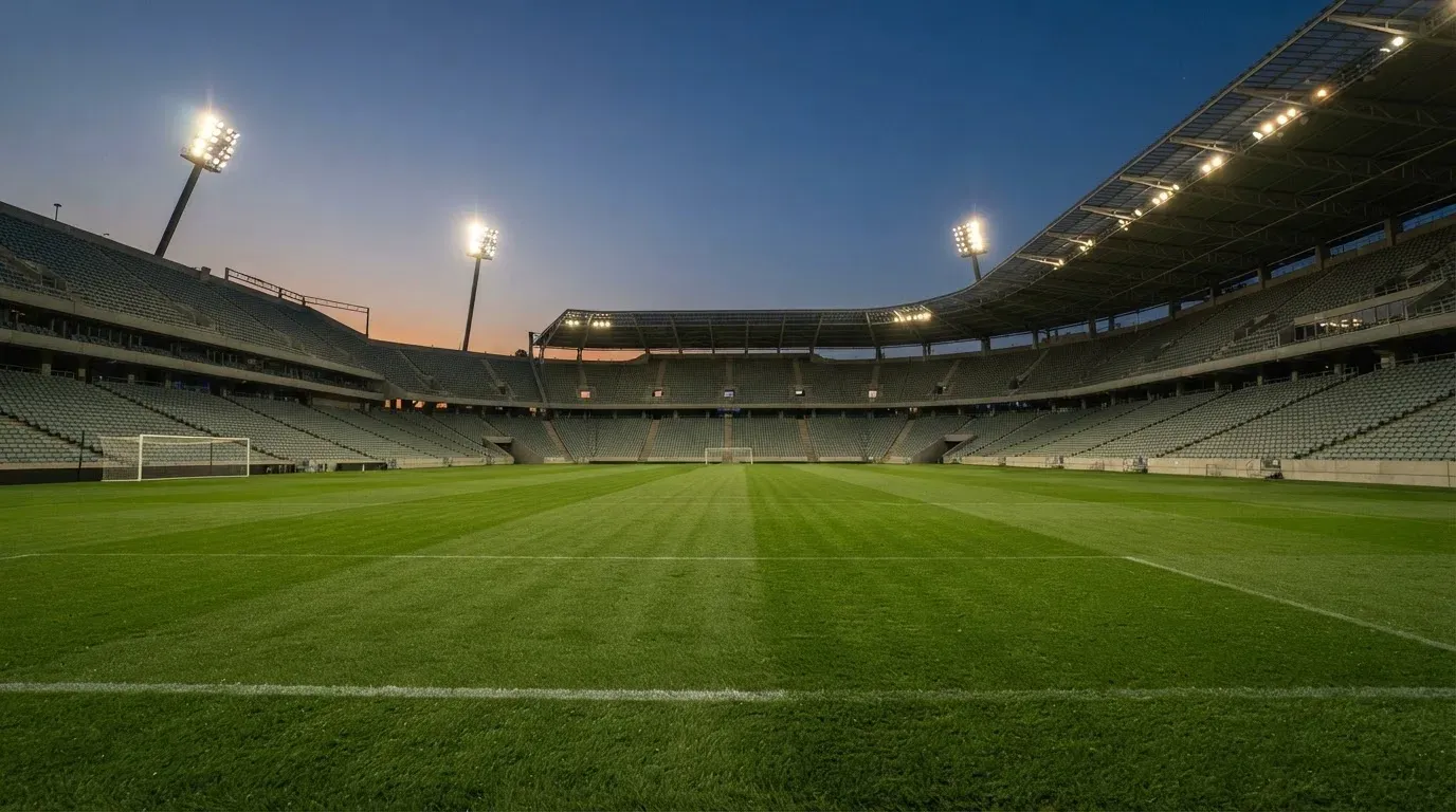 An empty football stadium with floodlight masts at dusk