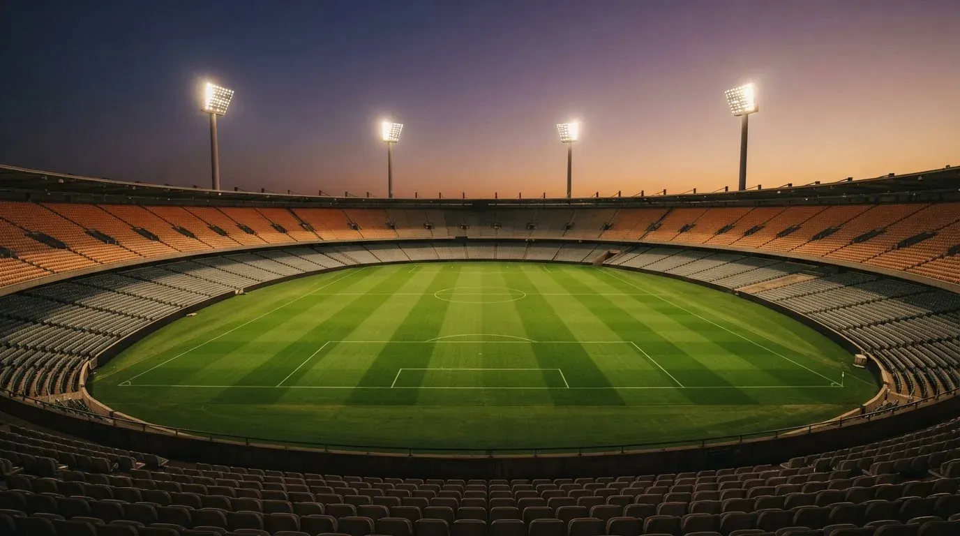 An empty football stadium with floodlight masts at dusk