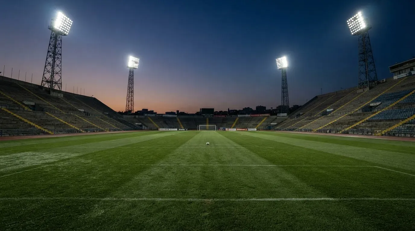 An empty football stadium with floodlight masts at dusk