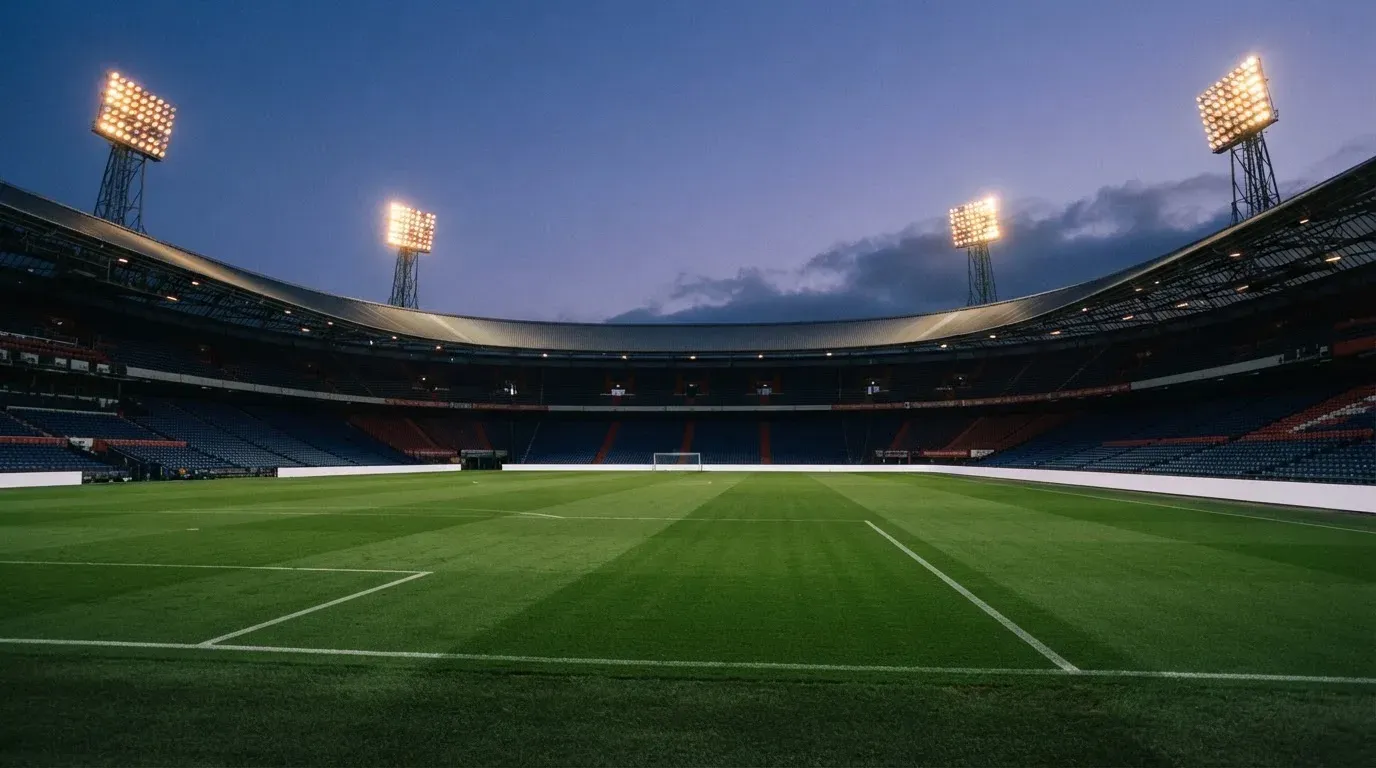 An empty football stadium with floodlight masts at dusk