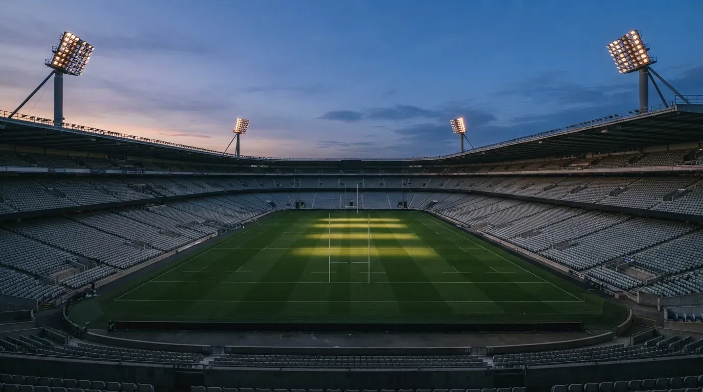 An empty football stadium with floodlight masts at dusk