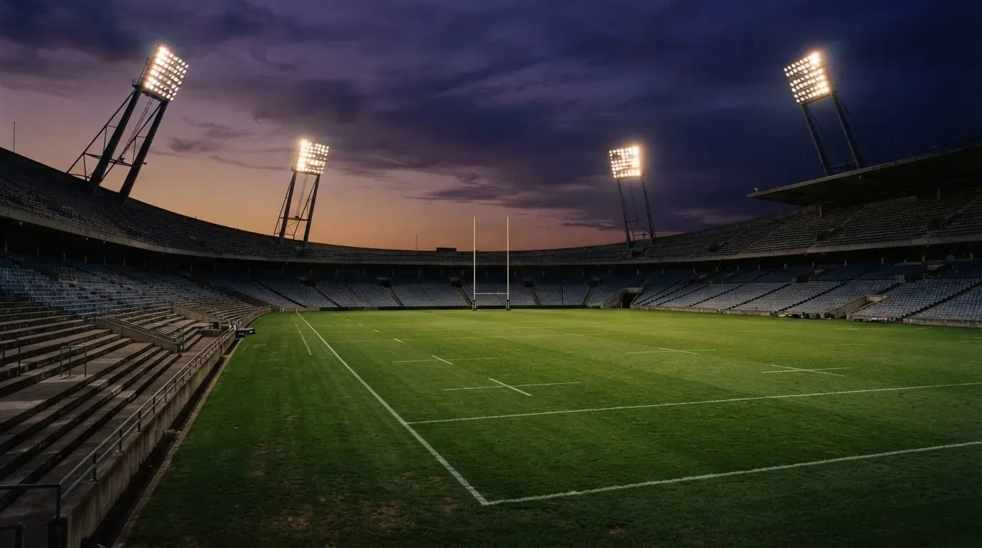 An empty football stadium with floodlight masts at dusk