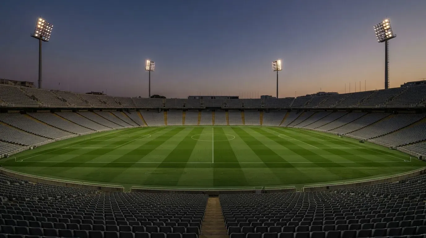 An empty football stadium with floodlight masts at dusk