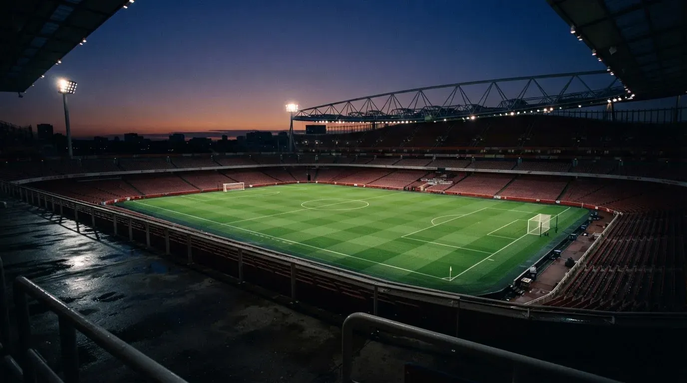 An empty football stadium with floodlight masts at dusk