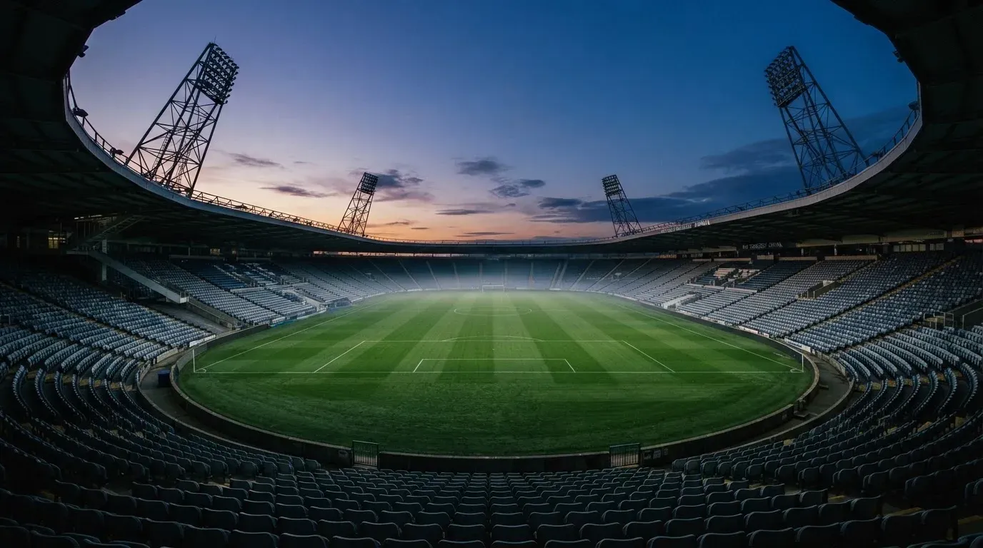 An empty football stadium with floodlight masts at dusk