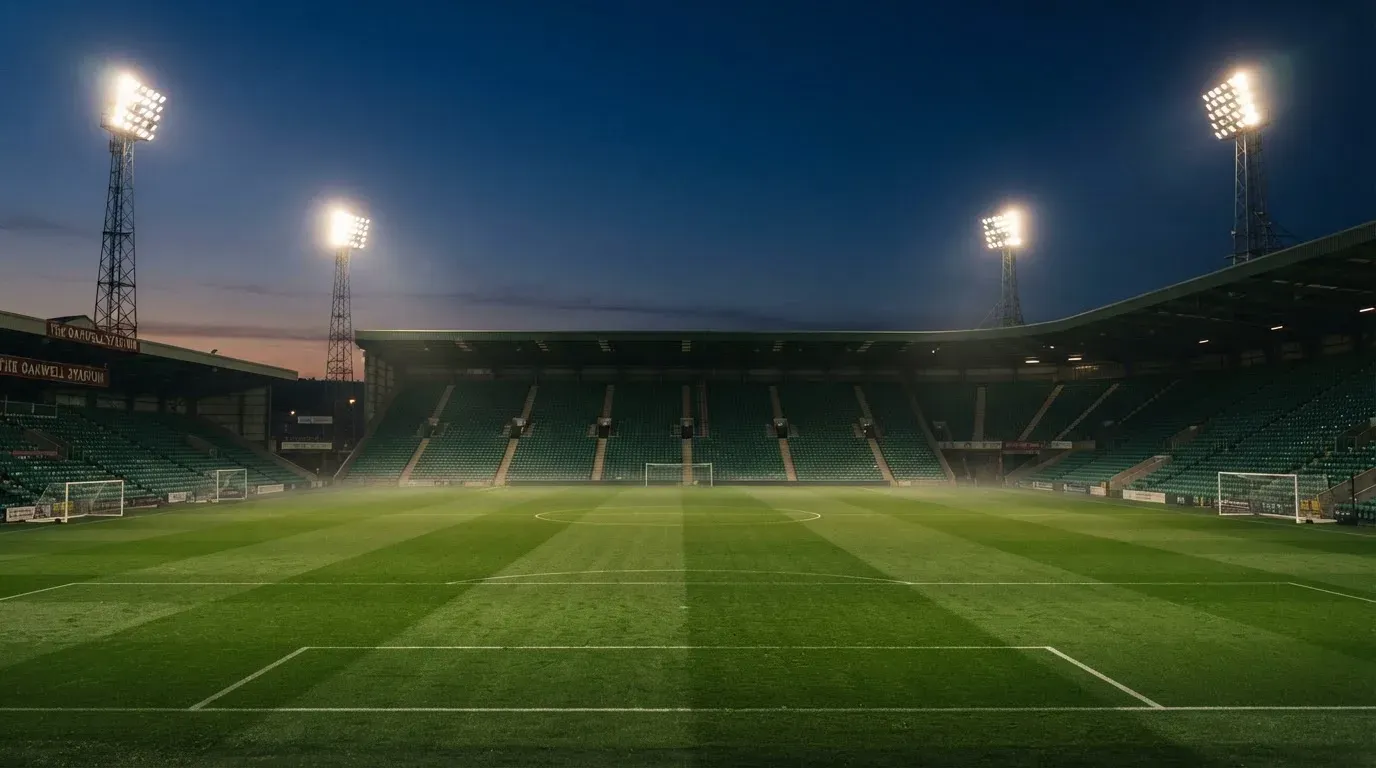 An empty football stadium with floodlight masts at dusk
