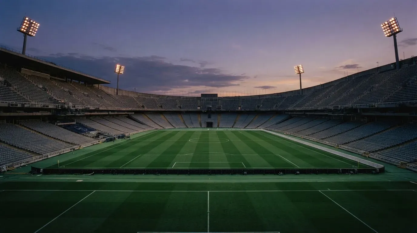 An empty football stadium with floodlight masts at dusk