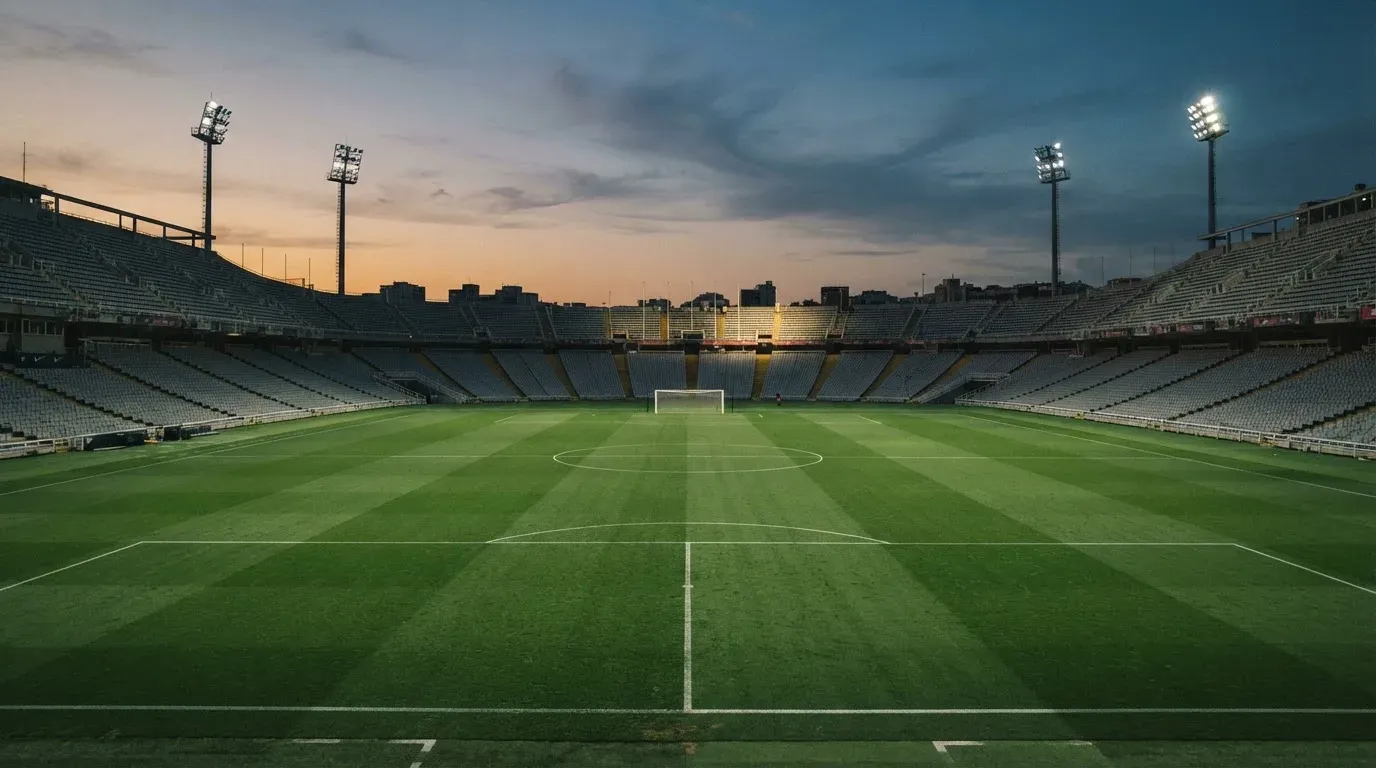 An empty football stadium with floodlight masts at dusk