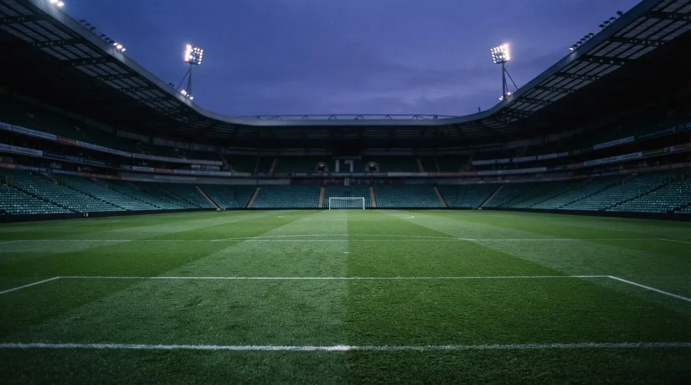 An empty football stadium with floodlight masts at dusk