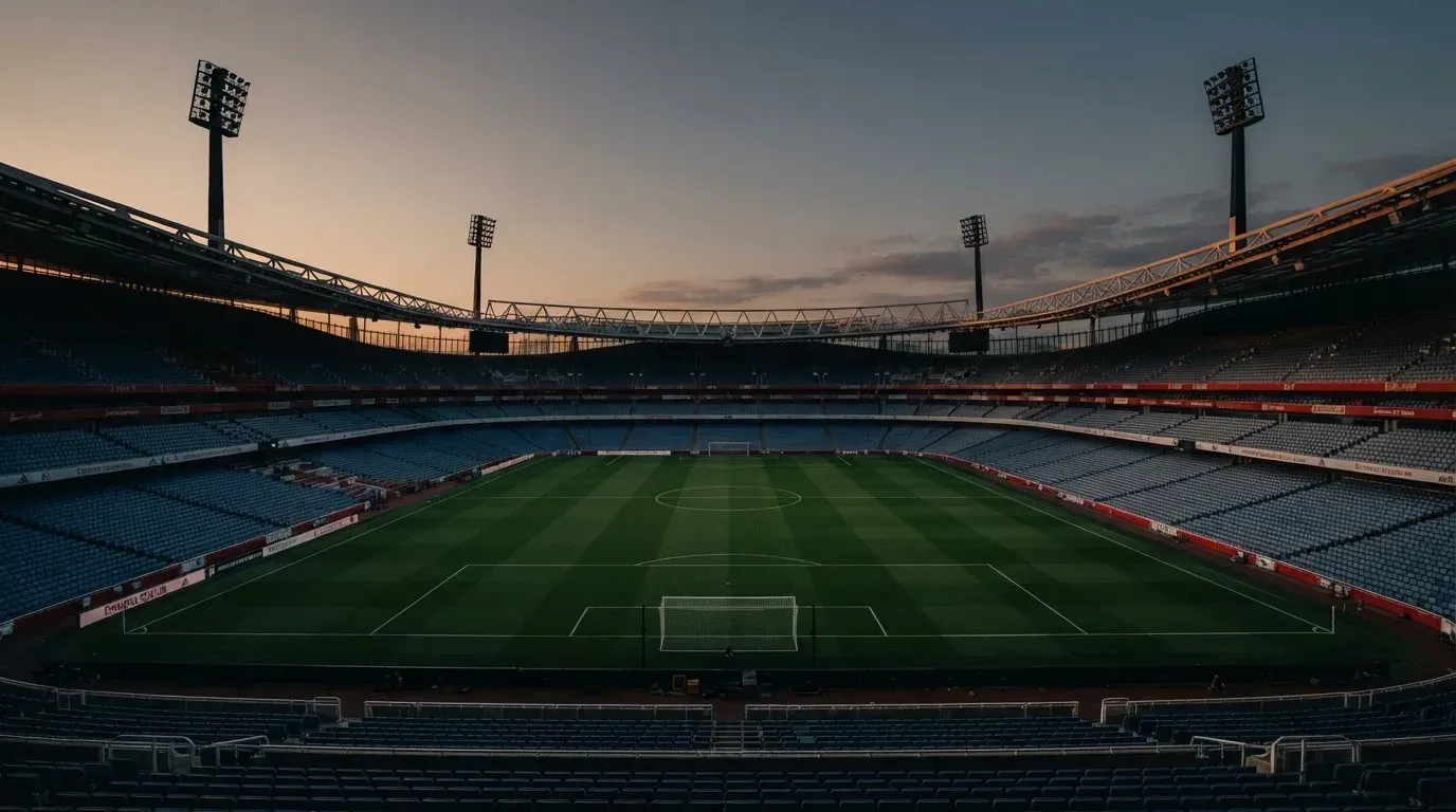 An empty football stadium with floodlight masts at dusk