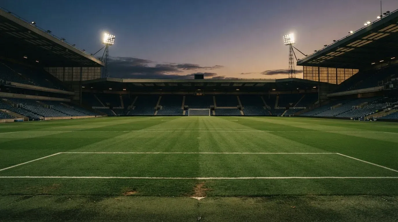 An empty football stadium with floodlight masts at dusk