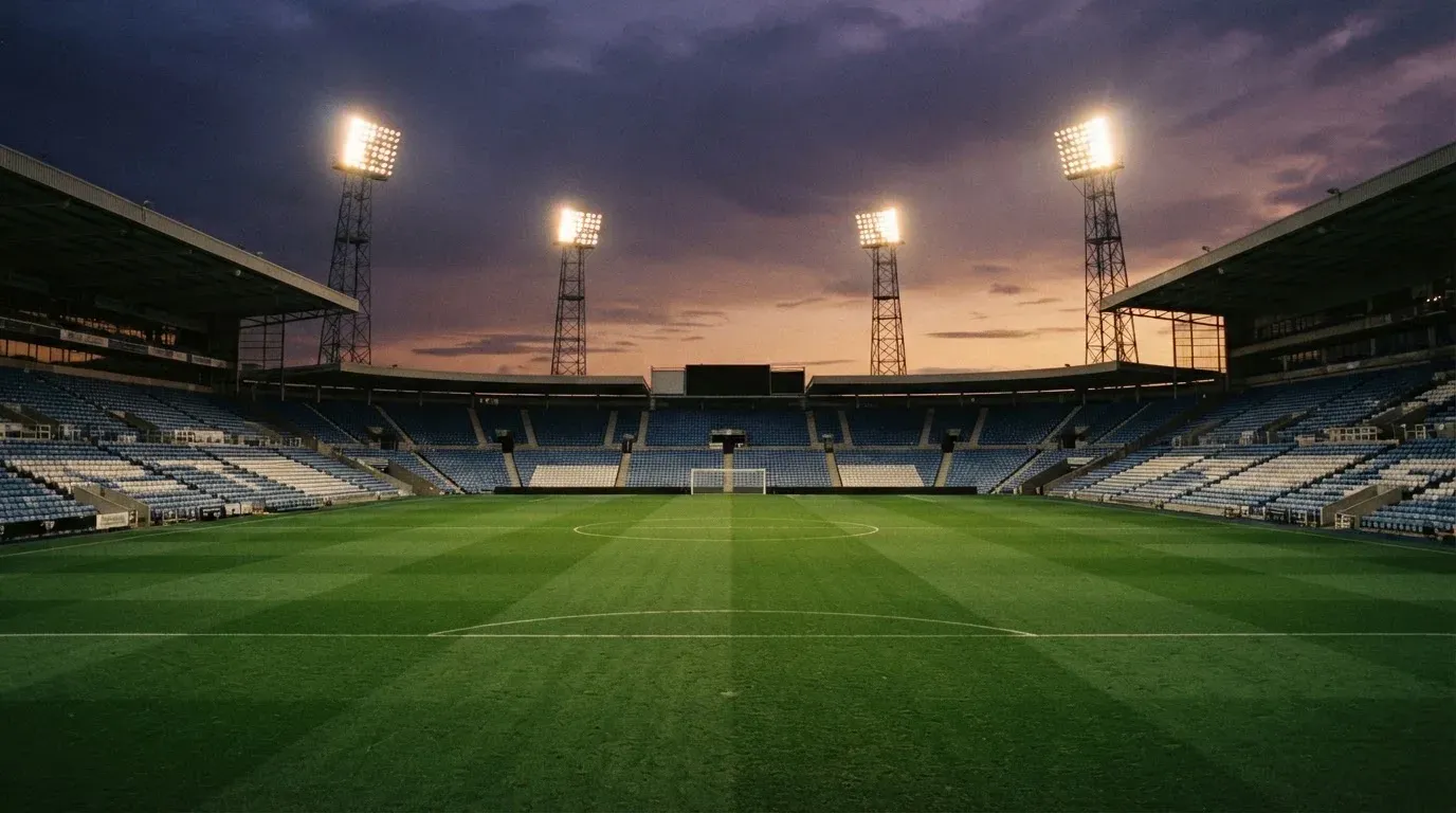 An empty football stadium with floodlight masts at dusk