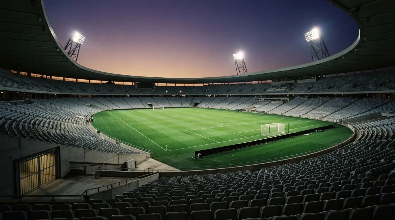 An empty football stadium with floodlight masts at dusk