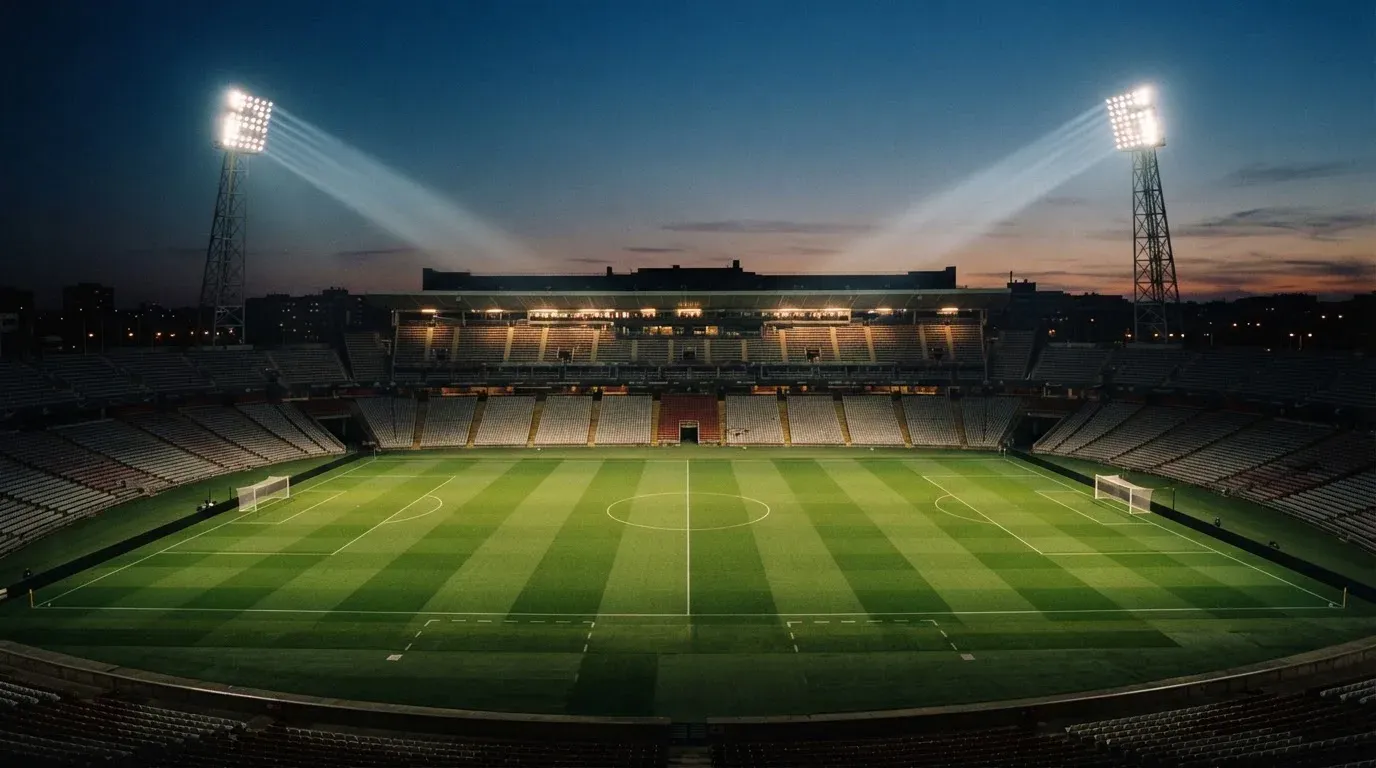 An empty football stadium with floodlight masts at dusk