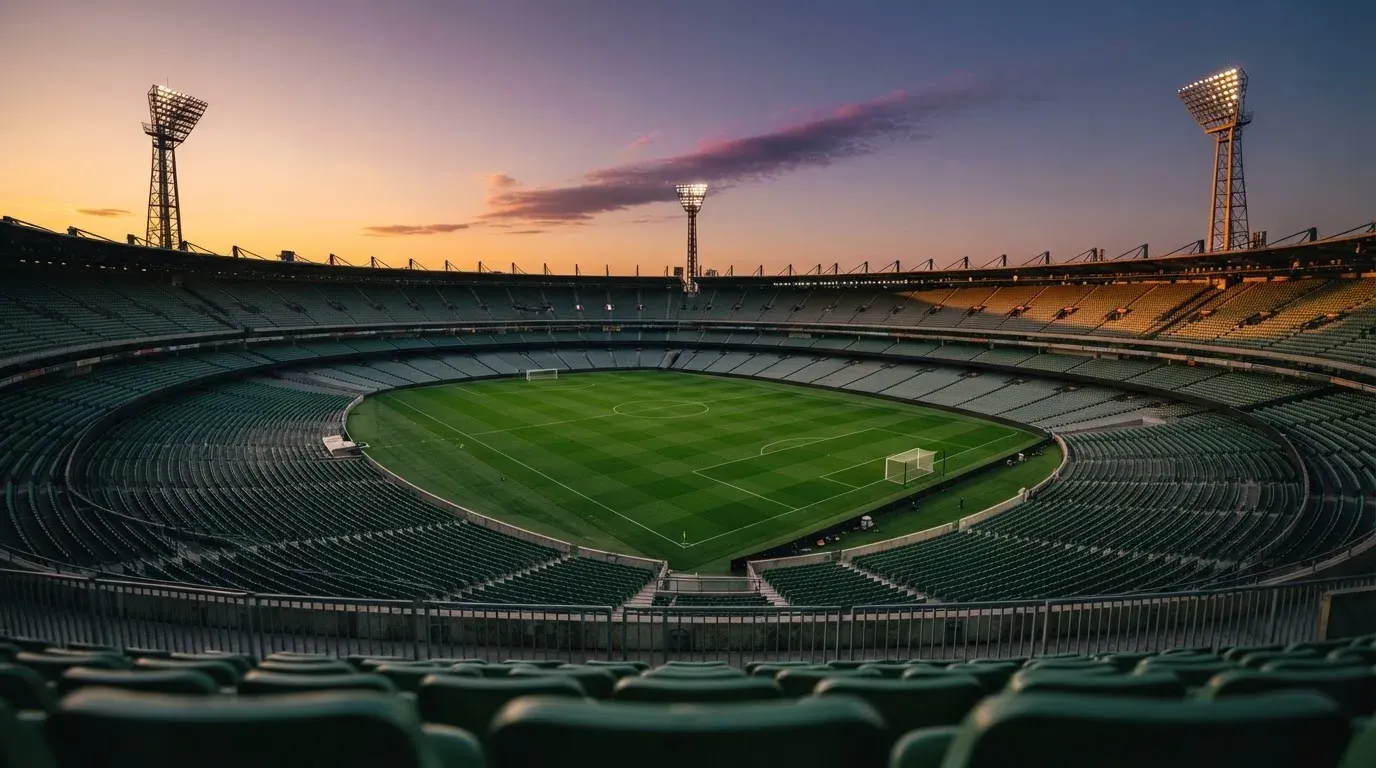An empty football stadium with floodlight masts at dusk
