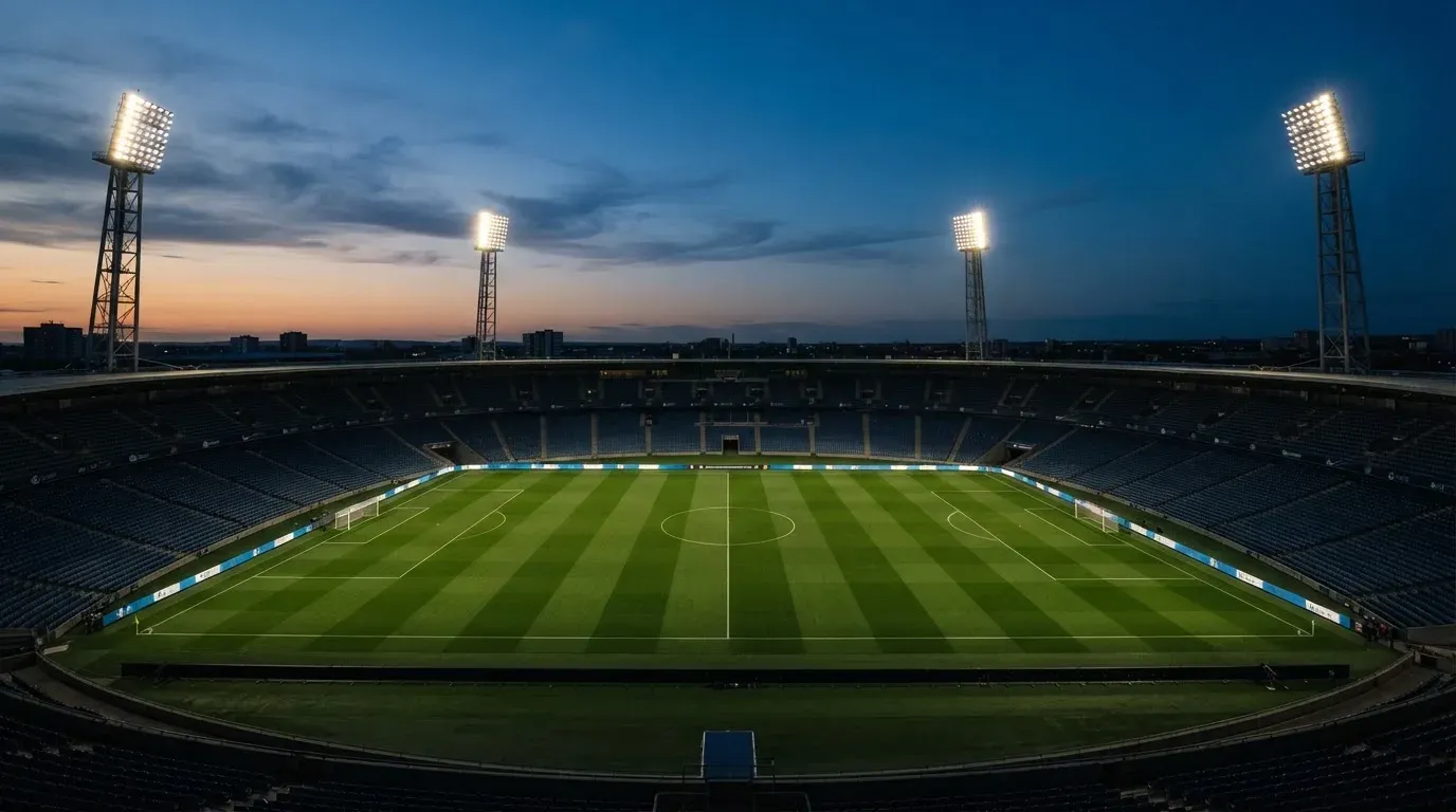 An empty football stadium with floodlight masts at dusk