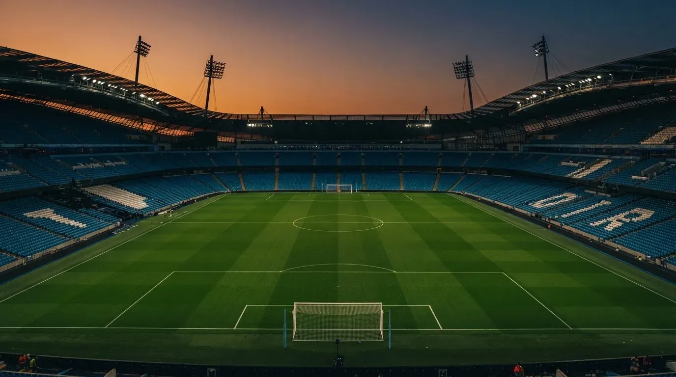 An empty football stadium with floodlight masts at dusk