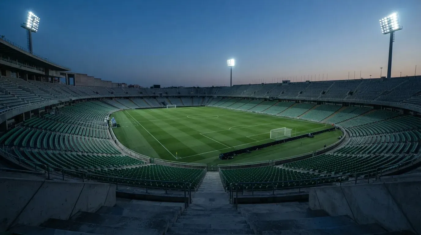 An empty football stadium with floodlight masts at dusk