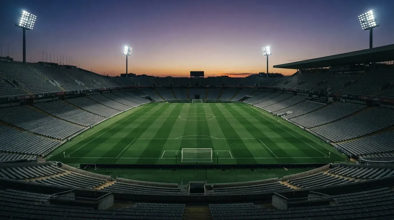 An empty football stadium with floodlight masts at dusk