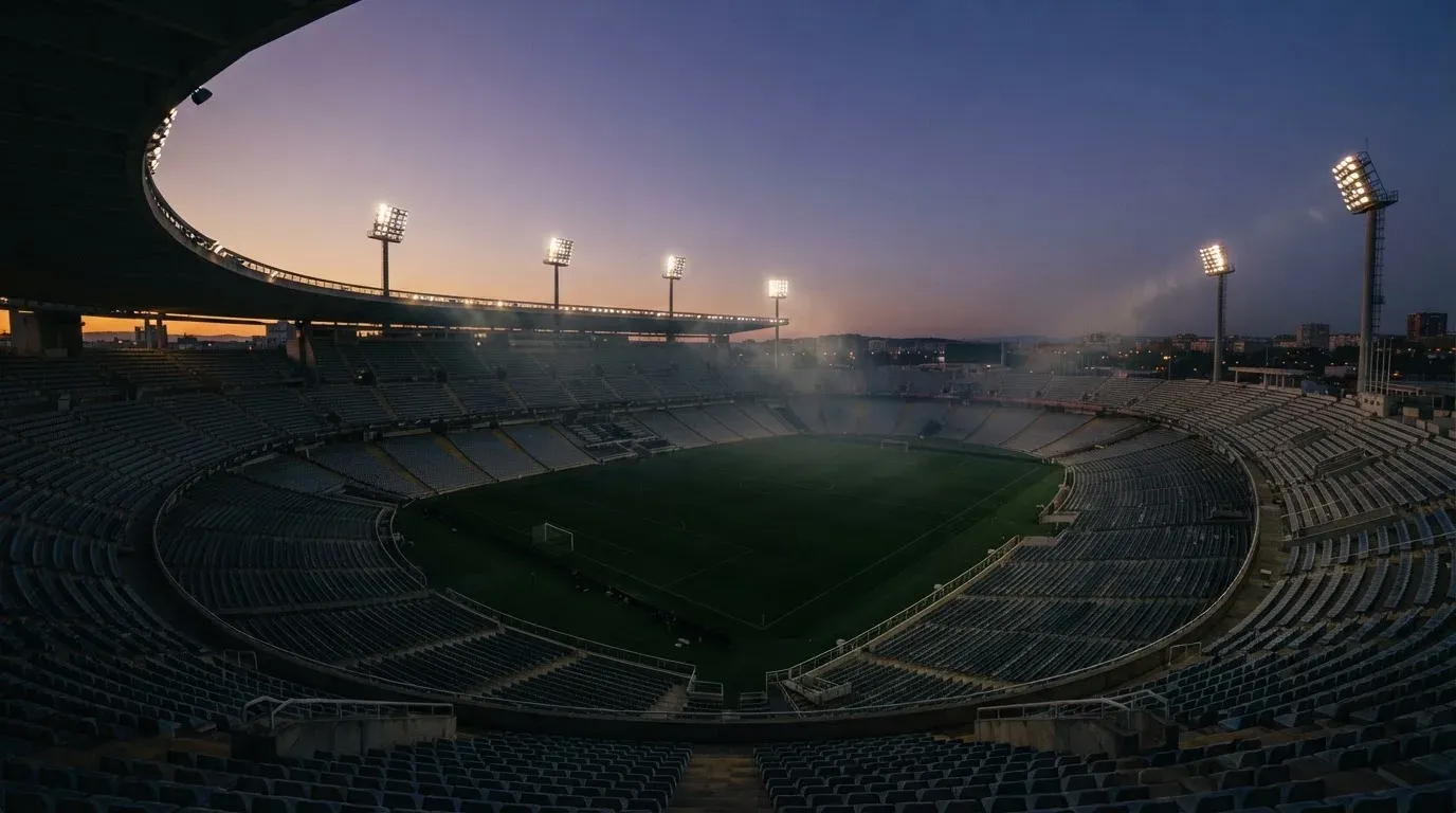 An empty football stadium with floodlight masts at dusk