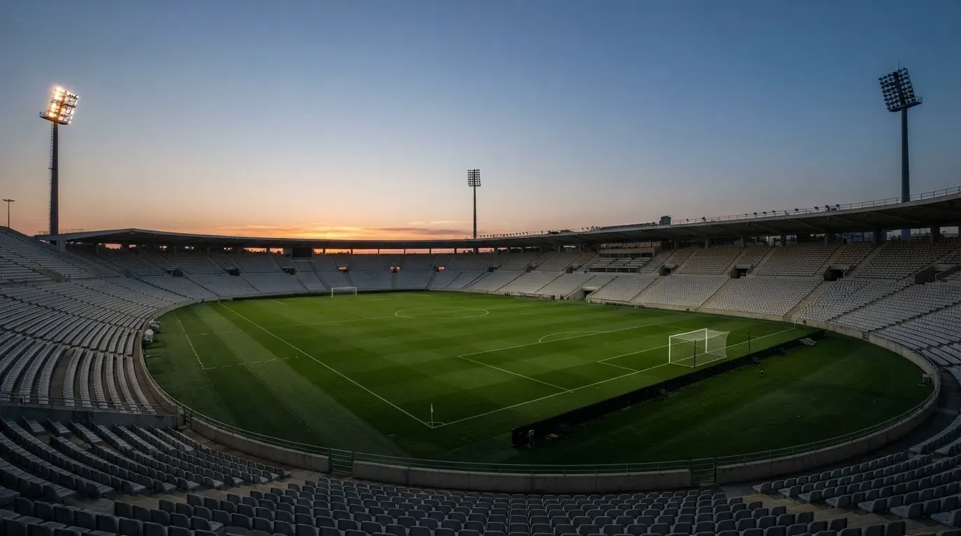 An empty football stadium with floodlight masts at dusk