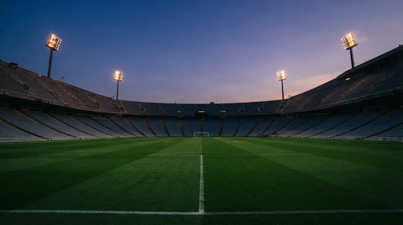 An empty football stadium with floodlight masts at dusk